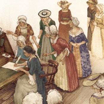 A group of women in historical clothing gather around a woman writing at a desk.