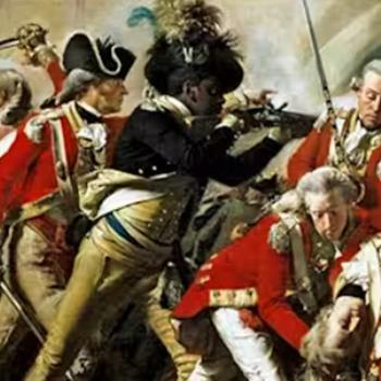 A Black soldier in a historic military uniform fights among white British soldiers in a chaotic battle scene.