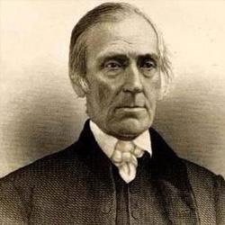 An older white man with short white hair and a serious expression, dressed in a dark suit with a white shirt and bow tie.