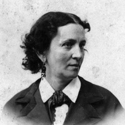 Black-and-white portrait of a woman with dark curly hair, wearing a jacket, blouse, and earrings.