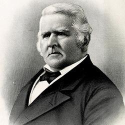 Black-and-white portrait of an older man with sideburns, wearing a dark suit and bow tie.