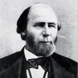 Black and white portrait of a man with a beard, wearing a suit and bow tie, facing forward.